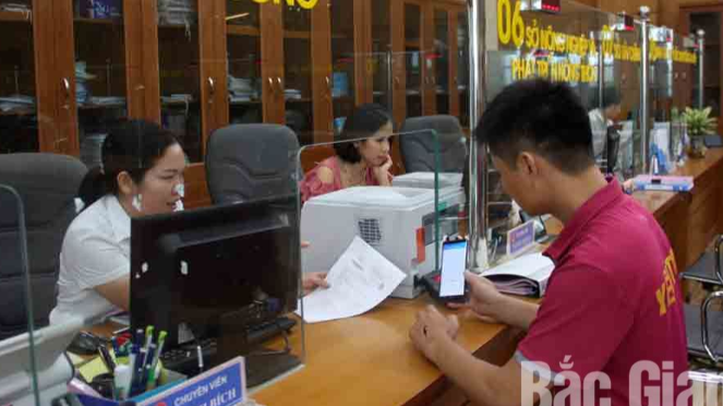 Cán bộ một cửa Sở Công thương Bắc Giang hướng dẫn người dân nộp hồ sơ trực tuyến