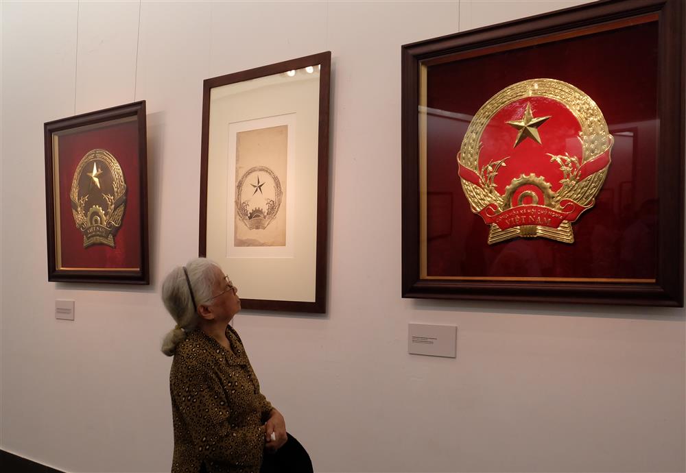 Bà Minh Tiến, con gái họa sĩ Bùi Trang Chước xúc động nhìn ngắm các mẫu Quốc huy do cha mình sáng tạo