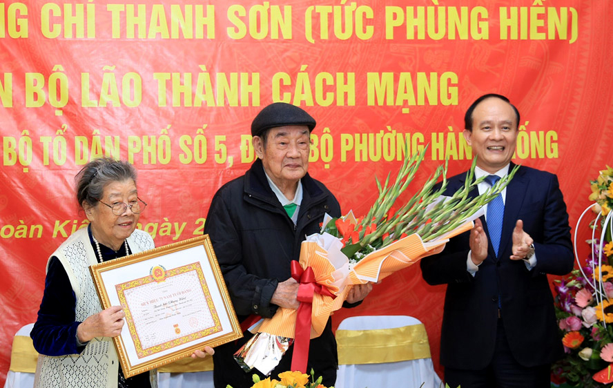 Phó Bí thư Thành ủy, Chủ tịch HĐND TP Hà Nội Nguyễn Ngọc Tuấn trao Huy hiệu 75 năm tuổi Đảng và tặng hoa chúc mừng đồng chí Phùng Thanh Sơn.