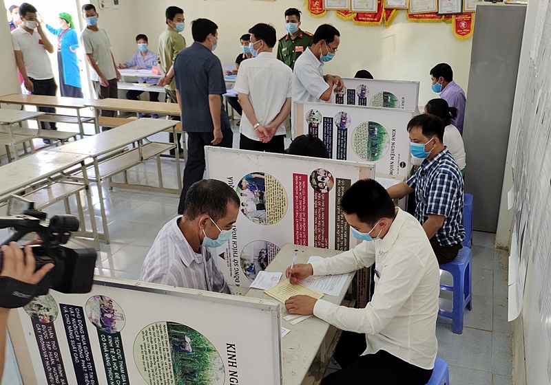 Cử tri xóm Tát, xã Tân Minh (Đà Bắc) tìm hiểu thông tin về đại biểu trước khi bỏ phiếu. Khu vực ghi phiếu được lắp đặt vách ngăn theo đúng quy định.