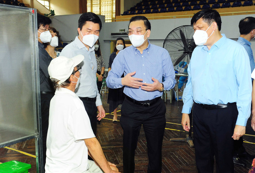 Bộ trưởng Bộ Y tế Nguyễn Thanh Long, Chủ tịch UBND thành phố Hà Nội Chu Ngọc Anh thăm hỏi một người cao tuổi sau khi được tiêm vắc xin phòng Covid-19.
