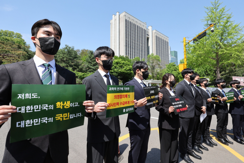 Các sinh viên y khoa giương biểu ngữ phản đối kế hoạch mở rộng tuyển sinh của chính phủ trước Tòa án quận trung tâm Seoul ngày 23.4. Ảnh: Yonhap